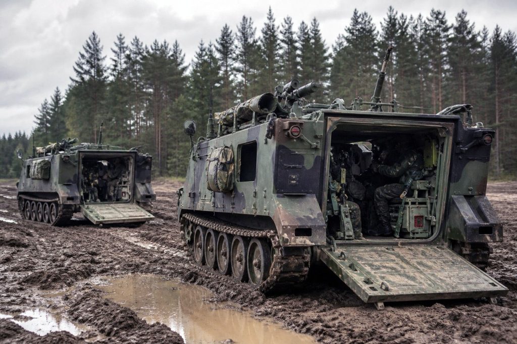 M113 armored personnel carrier operating in muddy terrain during field deployment, highlighting military vehicle lifecycle support and maintenance conditions